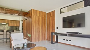 Ein modernes Wohnzimmer mit Fernseher, Essbereich und Küche.