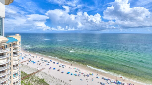 A beachfront hotel with a view of the ocean and a clear sky.