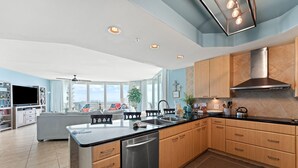 A modern kitchen with a central island, stainless steel appliances, and wooden cabinets. - Caribe C1010 (Orange Beach)