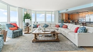 A spacious living room with a large window, a wooden coffee table, and a sofa with patterned cushions. - Caribe C1010 (Orange Beach)