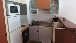 Eine kompakte Küche mit Mikrowelle, Geschirrspüler und einer kleinen Spüle.