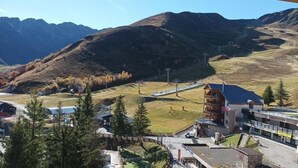 Eine Berglandschaft mit einer Seilbahn, einer Berghütte und einem kleinen Gebäude mit einem Schild.