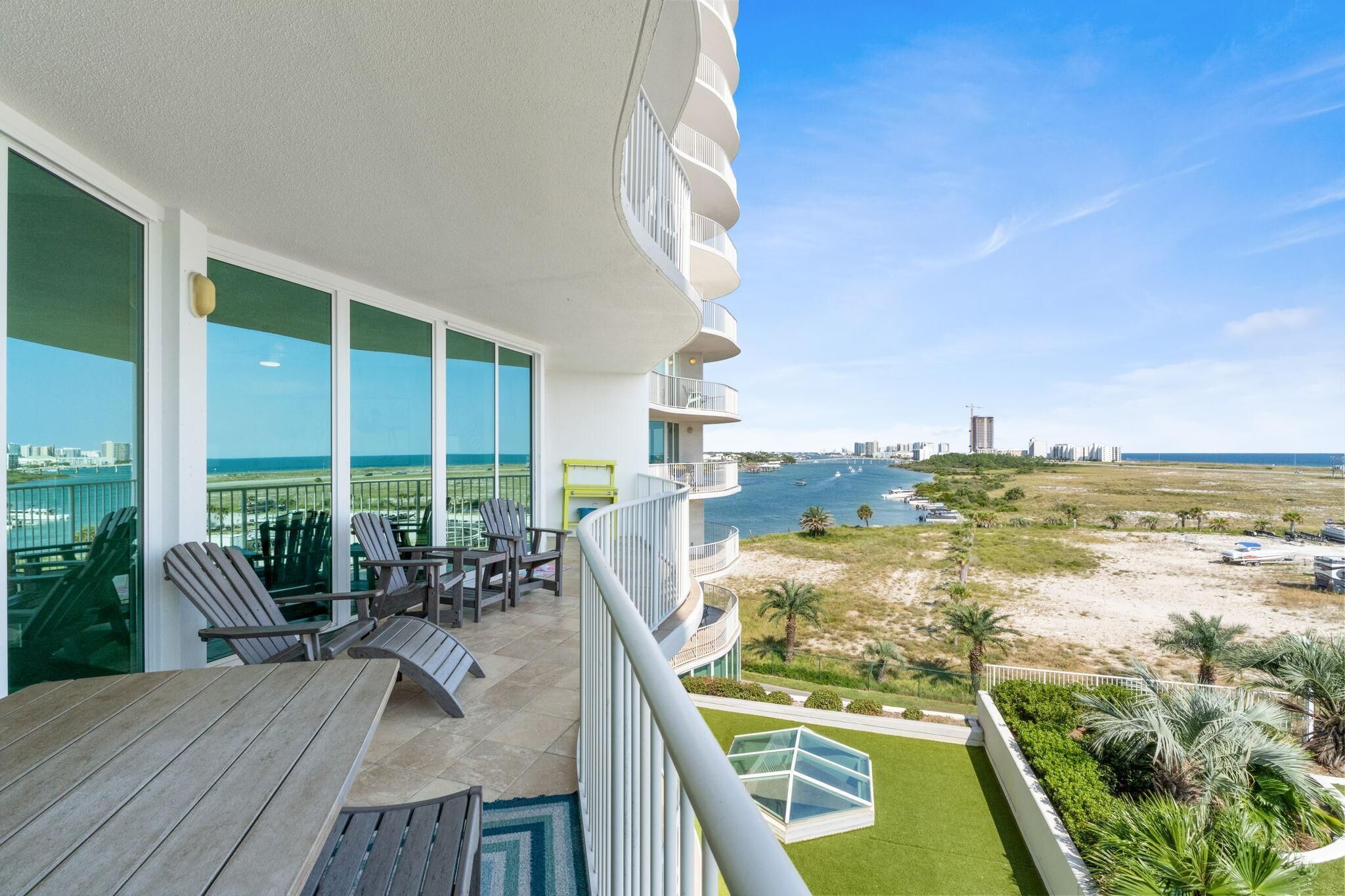Un balcone con vista sulla spiaggia e sull'oceano, con un tavolo e sedie in legno.