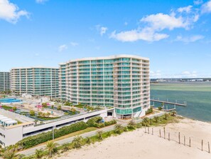 A modern hotel with multiple floors, a pool area, and a beach view. - Caribe D411 (Orange Beach)