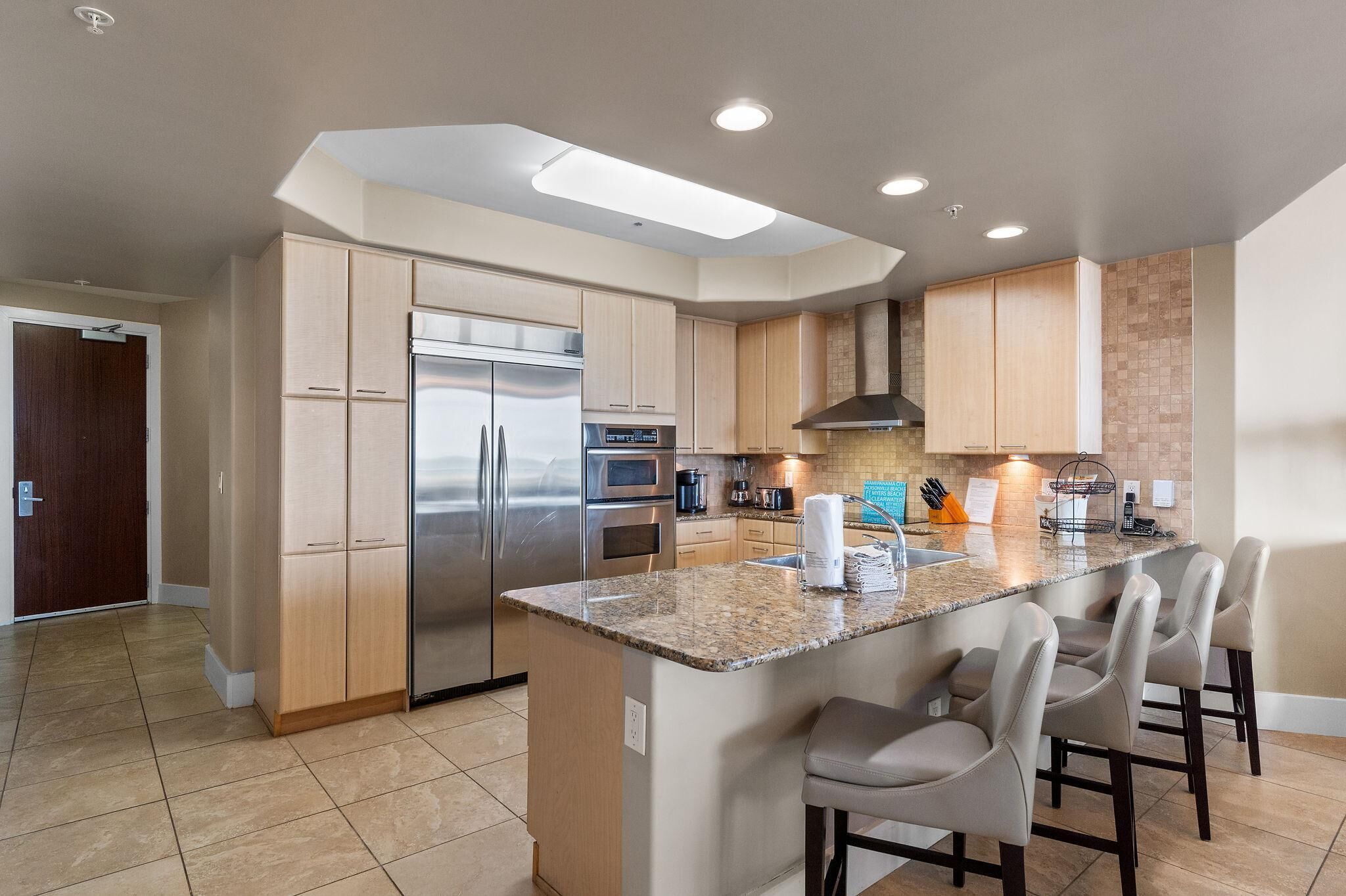 A modern kitchen with a central island, stainless steel appliances, and a breakfast bar.