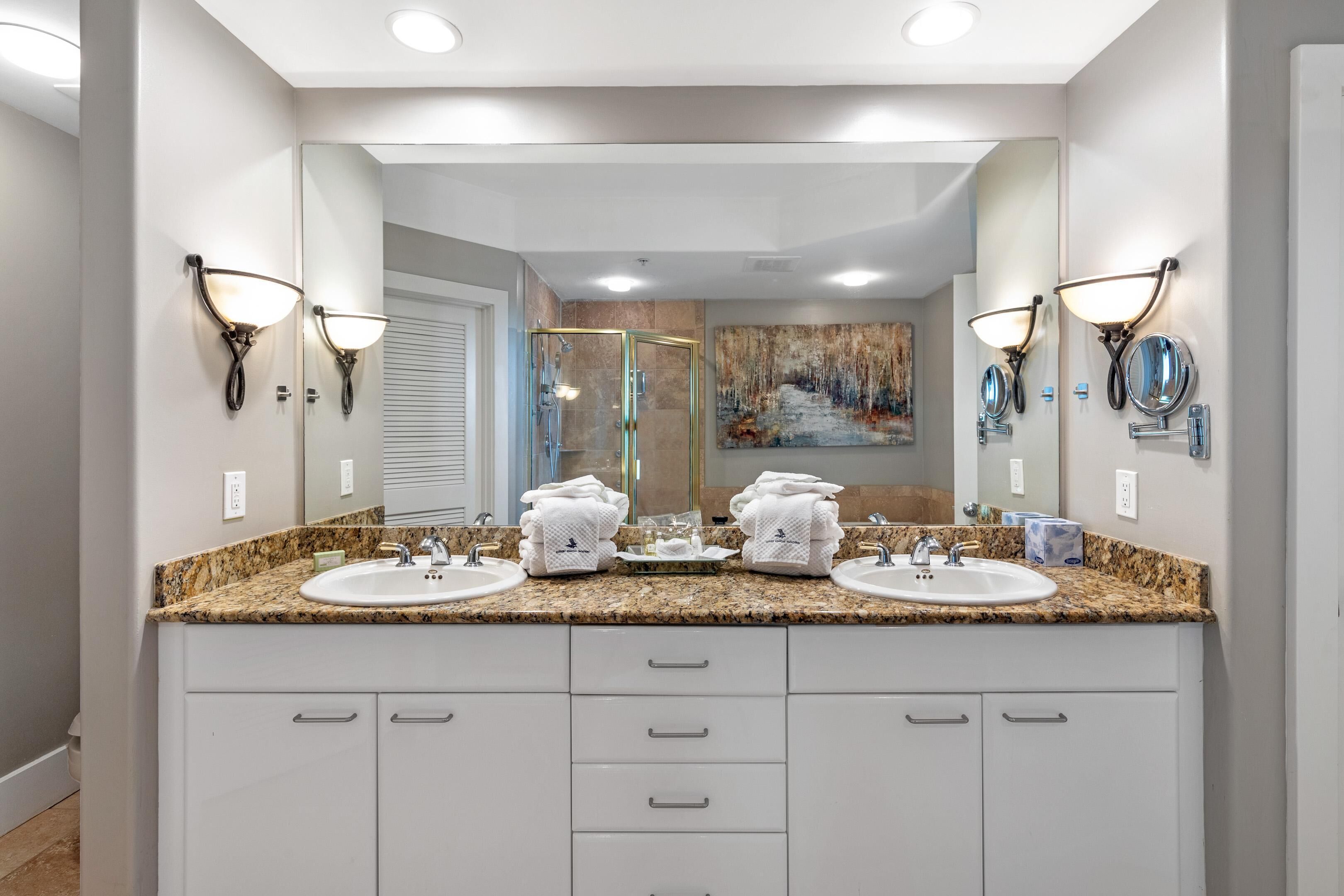 A bathroom with two sinks, a glass shower enclosure, and a large mirror.