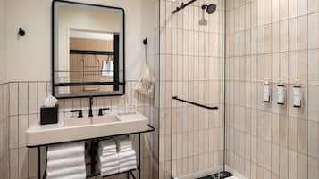 Un baño moderno con lavamanos, espejo, toallero y zona de ducha.