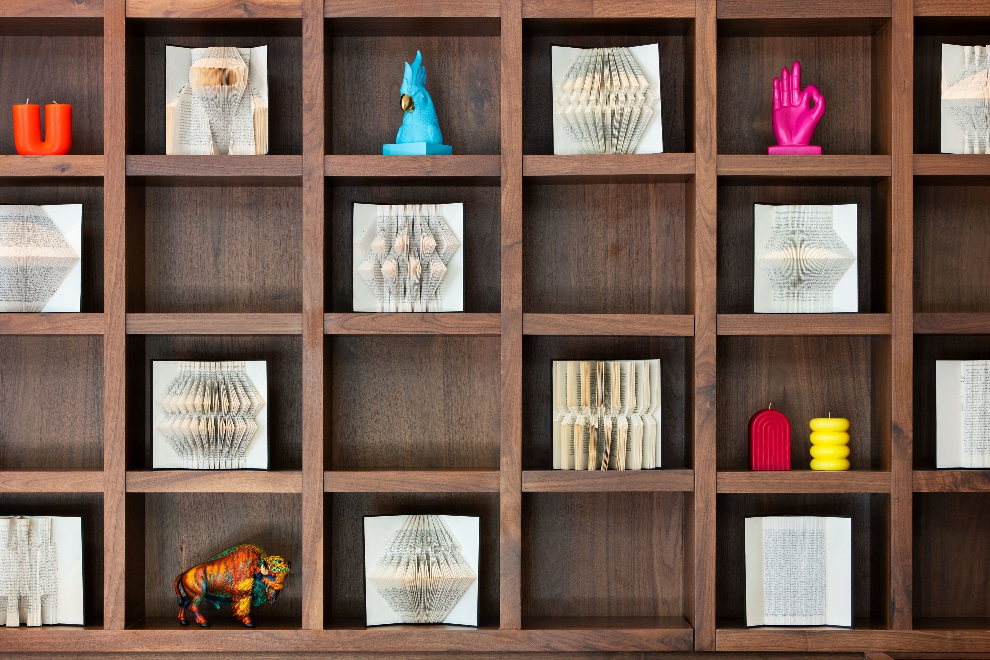 A wooden bookshelf with various decorative items and folded papers.