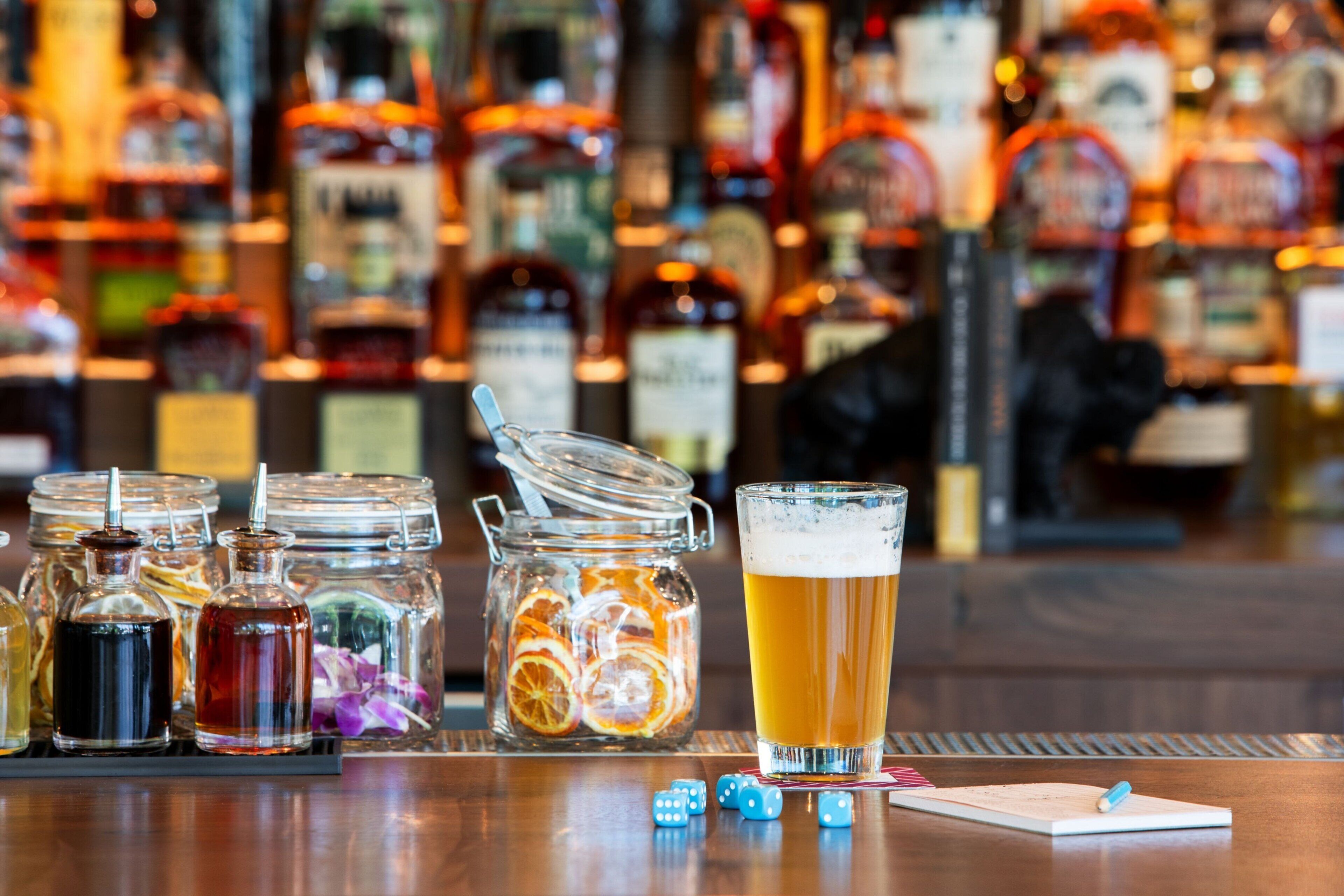 Un bar avec différentes bouteilles d’alcool et un verre de bière posés sur le comptoir.