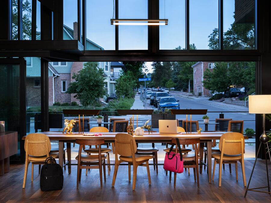 A modern dining area with wooden furniture, a laptop, and a handbag on the table.