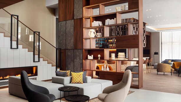 Una sala de estar moderna con chimenea, una escalera y una estantería llena de libros y objetos decorativos.