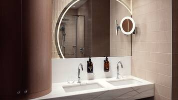 A modern bathroom with two sinks, a large mirror, and a shower area.