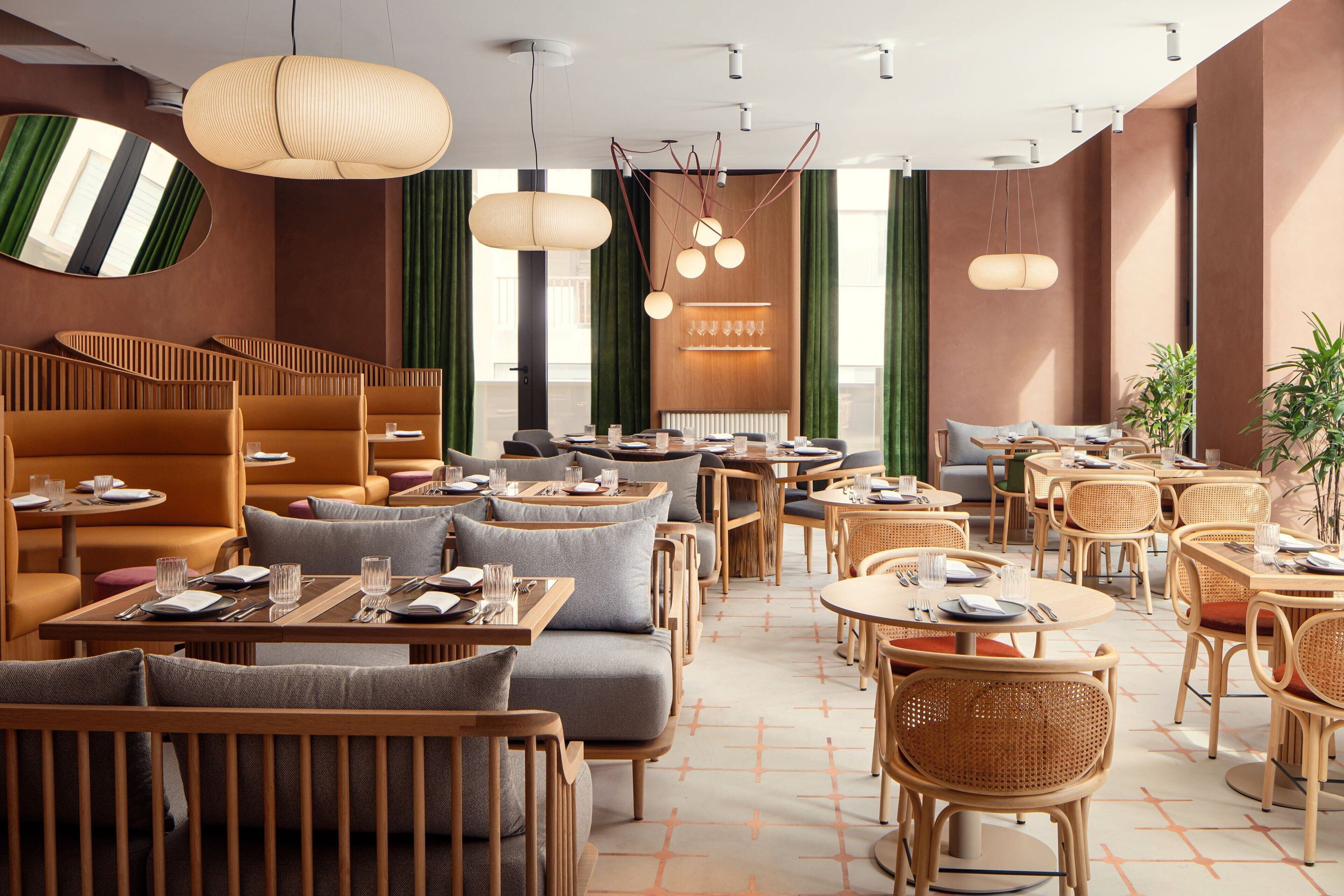 Un restaurant moderne avec des meubles en bois, des rideaux verts et des luminaires suspendus.