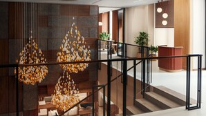 Un moderno vestíbulo de hotel con una escalera, un mostrador de recepción y un candelabro.