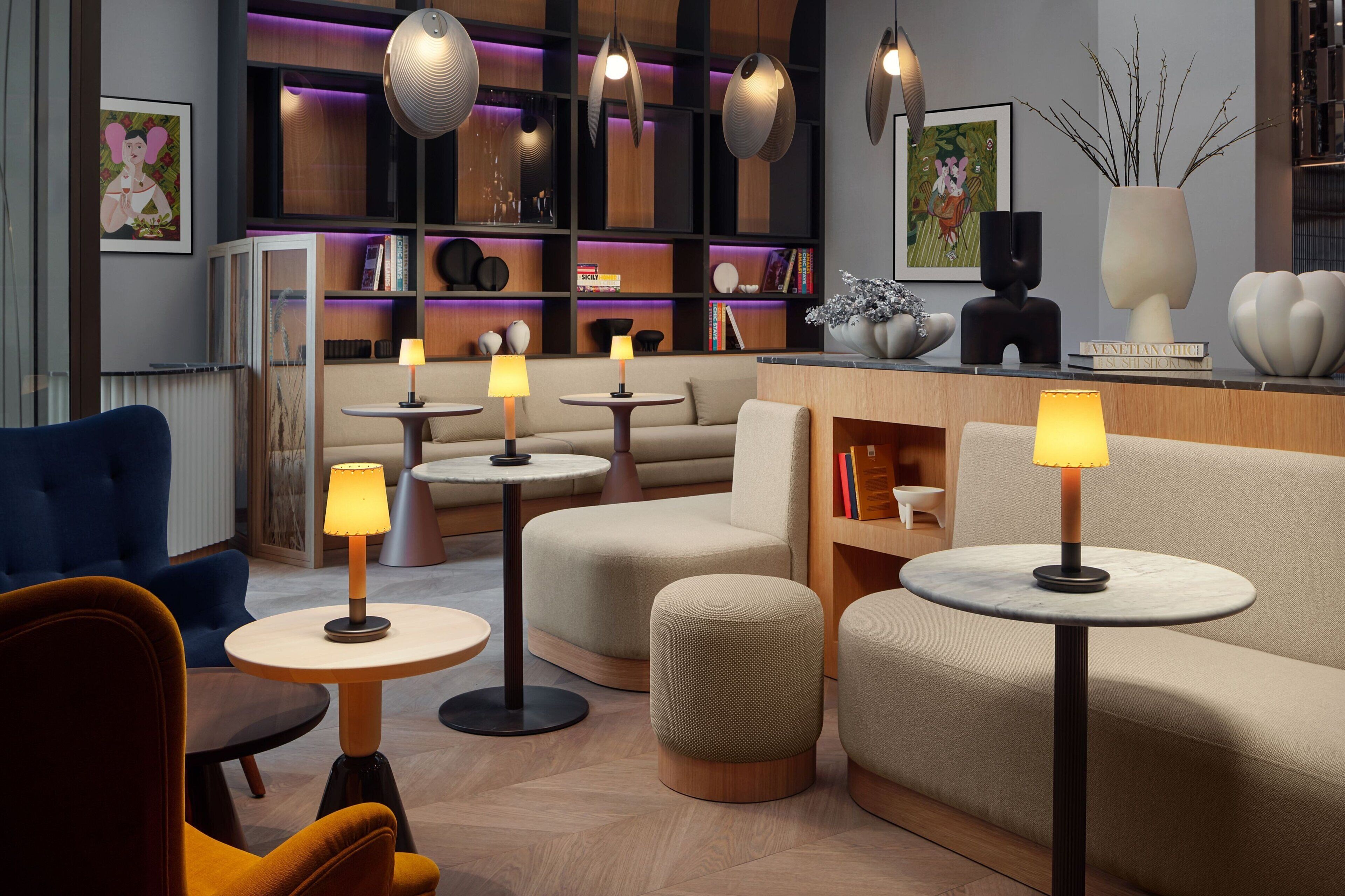 A modern lounge area with sofas, round tables, and pendant lighting.