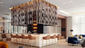 Una cocina moderna con una isla central, taburetes de bar y una zona de estar con sofás y sillones.