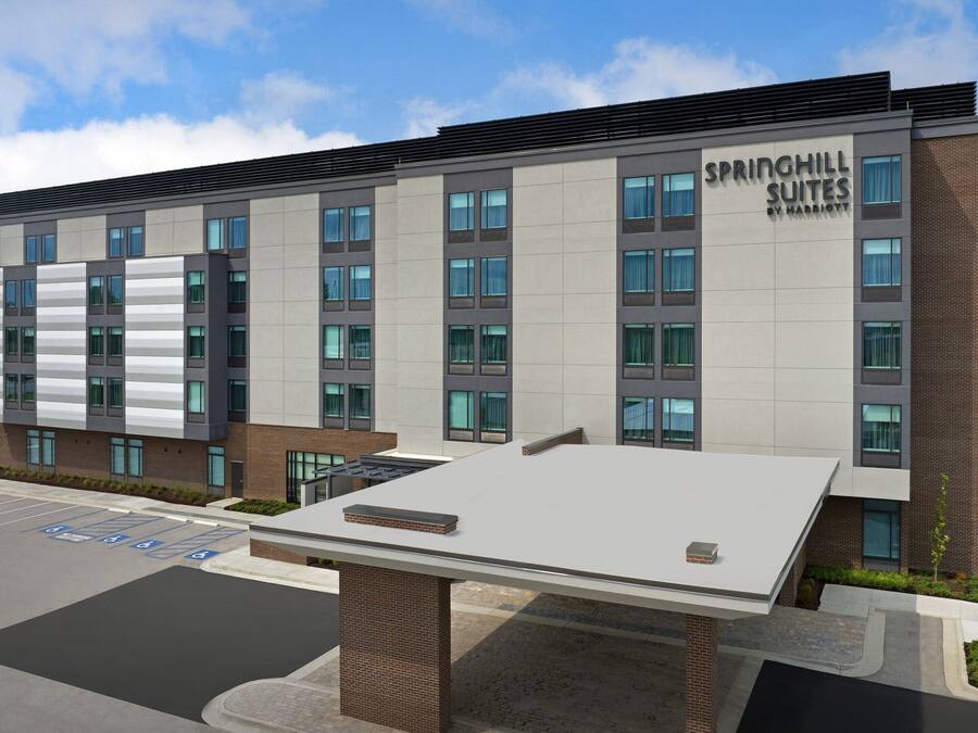 A modern hotel with a flat roof, large windows, and a sign reading "SPRINGHILL SUITES BY MARRIOTT".