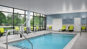 An indoor swimming pool with clear glass walls, yellow chairs, and a view of greenery outside. - Springhill Suites by Marriott Lexington Fritz Farm (Lexington)