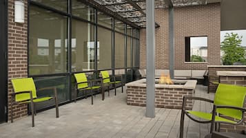 Un espace extérieur aménagé avec des murs en briques, de grandes fenêtres et un foyer.