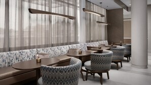 A modern restaurant with a long bench seating area, round tables, and patterned chairs. - Springhill Suites by Marriott Lexington Fritz Farm (Lexington)