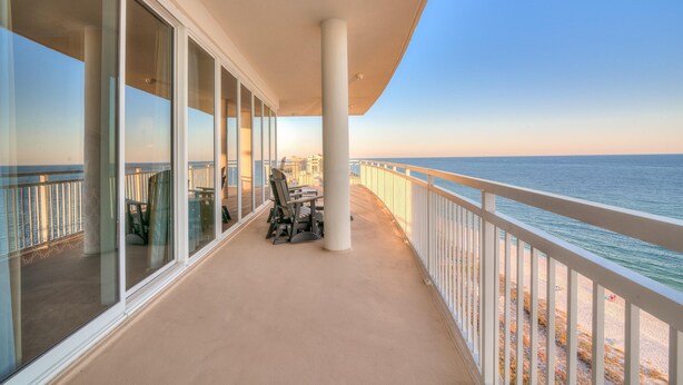 A balcony with a view of the ocean, a table with chairs, and a railing. - La Playa 1001 (Pensacola)