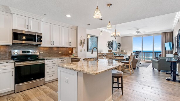 A modern kitchen with white cabinetry, stainless steel appliances, and a large island. - Spanish Key 305 (Pensacola)