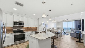 A modern kitchen with white cabinets, stainless steel appliances, and a large island. - Spanish Key 305 (Pensacola)