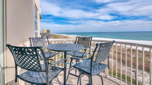 A balcony with metal chairs and a table overlooking a beach and ocean. - Spanish Key 305 (Pensacola)