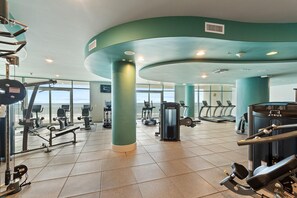 A gym with various exercise equipment, large windows, and teal-colored walls. - Turquoise C702 (Orange Beach)