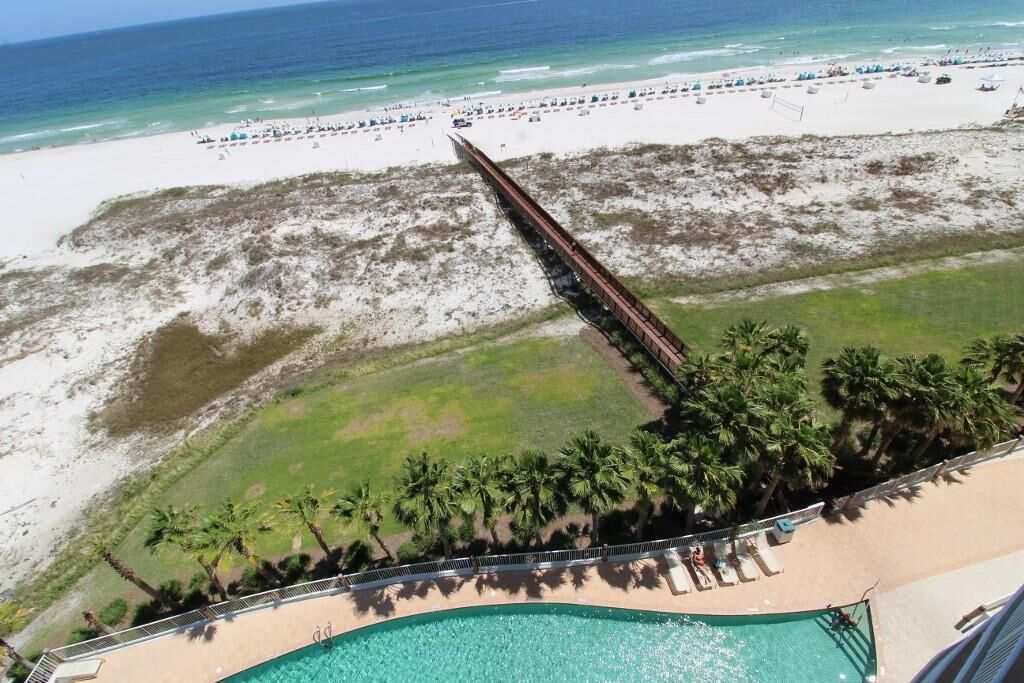 A resort with a swimming pool, beach, and palm trees.