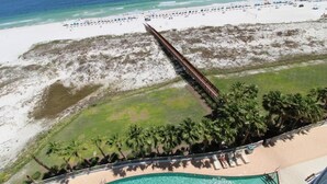 A resort with a swimming pool, beach, and palm trees. - Turquoise C702 (Orange Beach)