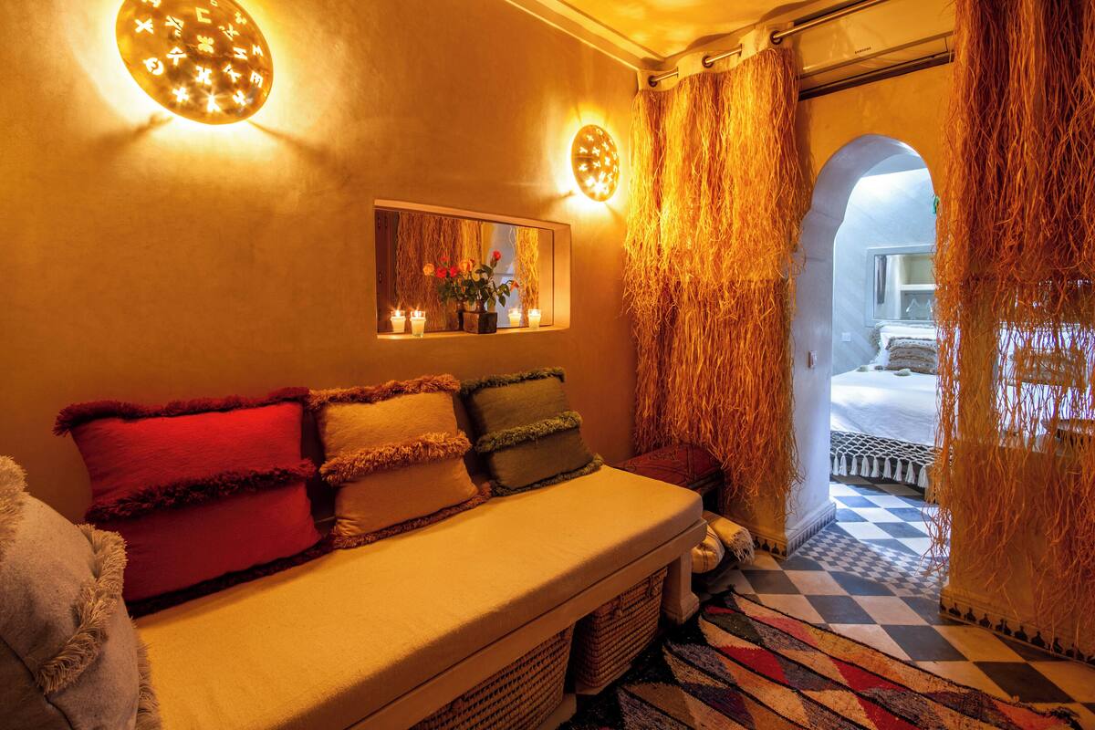 A cozy room with a bed, a mirror, and a window with curtains.