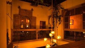 Una habitación cálidamente iluminada con muebles de madera, paneles decorativos y vistas por una ventana.