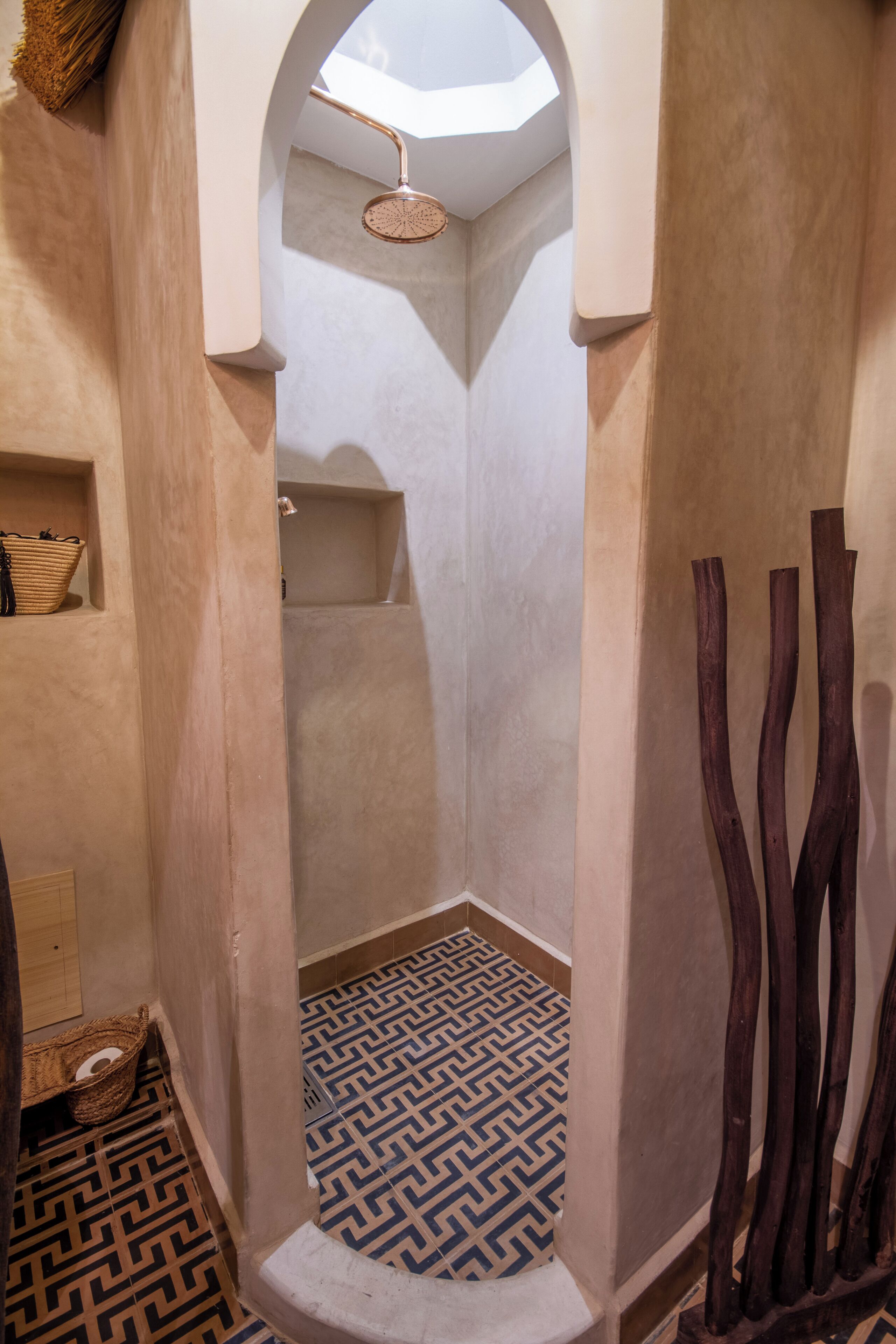 A narrow hallway with a patterned floor, a shower area, and a wooden structure on the right.