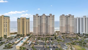 A coastal high-rise hotel with multiple floors, a parking area, and a view of the ocean. - Indigo West 1101 (Pensacola)