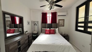 A bedroom with a bed, a dresser, a bedside table, a hanging chair, a ceiling fan, and a window with curtains. - Coastal Paradise Steps from Secluded Beaches & Stunning views in Islote, Arecibo (Islote)