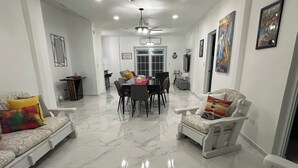 A spacious living area with a dining table and chairs, a sofa, and a white armchair. - Coastal Paradise Steps from Secluded Beaches & Stunning views in Islote, Arecibo (Islote)