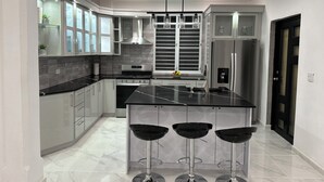 A modern kitchen with a central island, stainless steel appliances, and a black countertop. - Coastal Paradise Steps from Secluded Beaches & Stunning views in Islote, Arecibo (Islote)