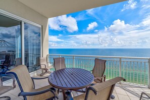 A balcony with a round table and chairs, overlooking a clear blue sea and sky. - Indigo West 2103 Penthouse (Pensacola)