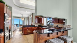 Una cucina moderna con mobili in legno scuro, un'isola grande con sgabelli da bar e vista all'esterno.