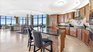 A spacious kitchen with a large island, wooden cabinets, and a view of the ocean. - Capri 302 (Pensacola)