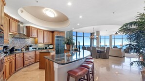 A spacious kitchen with a large island, wooden cabinets, and a view to the outside. - Capri 601 (Pensacola)