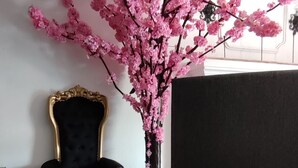 Une pièce avec une table ronde en marbre, une chaise noire et dorée, et un vase rempli de fleurs roses.