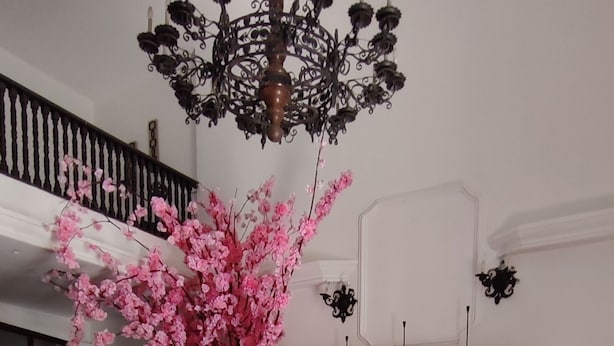 Un coin repas avec une table en bois foncé, un vase rempli de fleurs roses et un lustre.