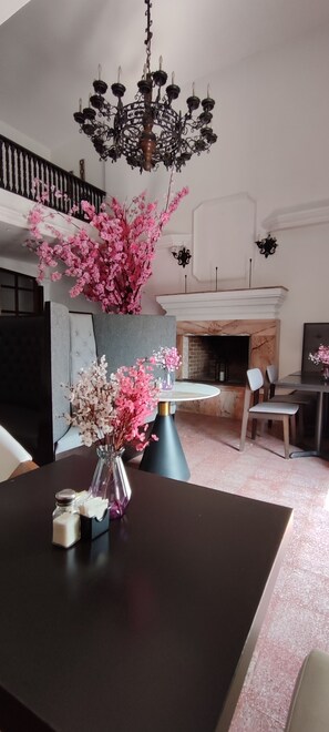 Un coin repas avec une table en bois foncé, un vase rempli de fleurs roses et un lustre.