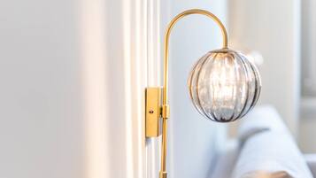 Una lámpara de pared con pantalla de cristal esférica y brazo dorado.