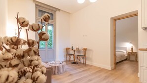 Een moderne slaapkamer met een houten vloer, een grote spiegel, een bed en een klein tafeltje met stoelen.
