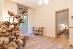 Une chambre à coucher moderne avec un plancher en bois, un grand miroir, un lit et une petite table avec des chaises.