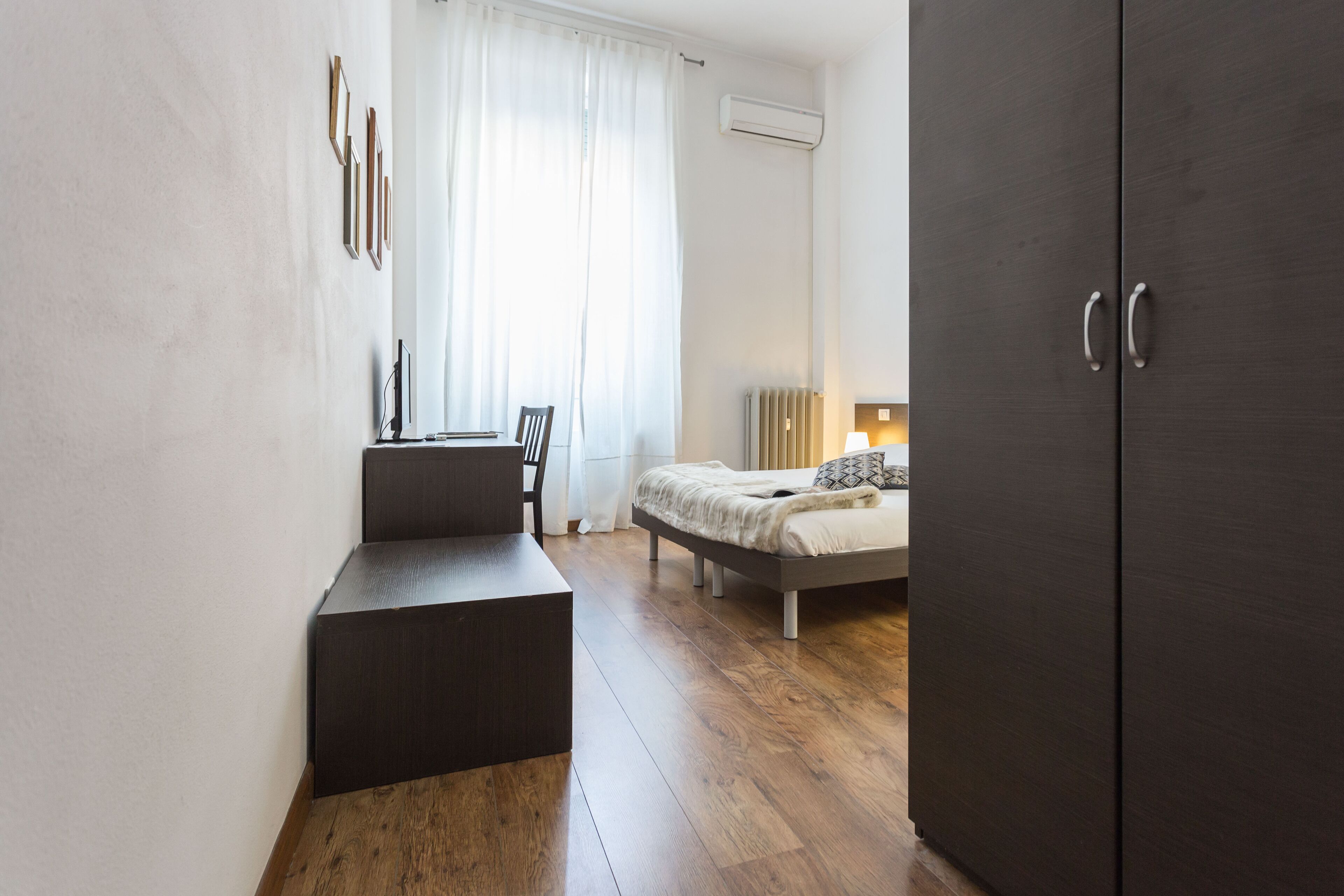 Un dormitorio moderno con cama, escritorio y armario.