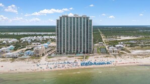 A high-rise hotel with multiple floors, a beach in the foreground, and a view of the surrounding landscape.